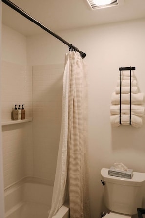 Une salle de bain équipée d’un rideau de douche, de toilettes et d’un porte-serviettes avec des serviettes.
