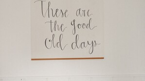 A framed sign with the text "These are the good old days" hanging on a white wall. - The Midnight Room - #22 (Whitehall)