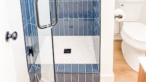A modern bathroom with a glass-enclosed shower, a toilet, and a sink. - The Midnight Room - #22 (Whitehall)