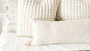 A bed with white bedding and a brown quilt.
