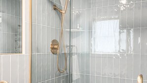 Une salle de bain moderne avec une douche à parois de verre, un lavabo blanc et un meuble-lavabo en bois.