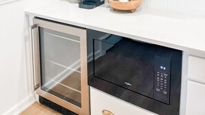 Een keuken met witte kasten, houten planken, een koffiezetapparaat, een kom en een vaatwasser.