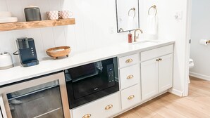 Een moderne keuken met witte kastjes, een inbouwoven en een koffiezetapparaat.