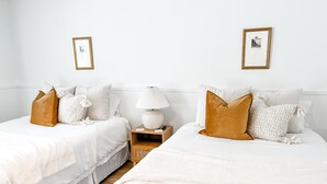 A hotel room with two beds, white bedding, and a nightstand with a lamp. - The Goldie Room - #21 (Whitehall)