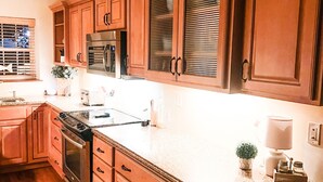 Een keuken met houten kastjes, roestvrijstalen apparatuur en een granieten aanrecht.