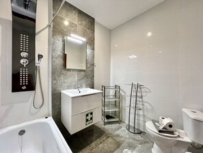 Un baño moderno con bañera, lavamanos, espejo y retrete.