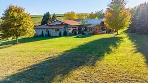 A stone house with a metal roof, surrounded by a grassy field and trees. - VellaVue Luxury Estate: Private Indoor Pool, Sauna, Gym & Theater – Sleeps 20 (Friendsville)