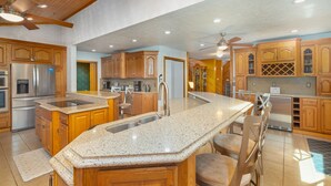 A spacious kitchen with wooden cabinets, granite countertops, stainless steel appliances, and a large island with seating. - VellaVue Luxury Estate: Private Indoor Pool, Sauna, Gym & Theater – Sleeps 20 (Friendsville)