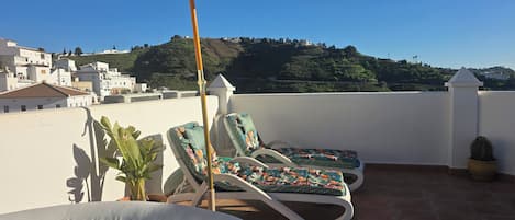 Terraza en la azotea con bañera de hidromasaje, sillones de descanso y sombrilla.
