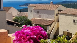 Ein Küstendorf mit terrakottafarbenen Dächern, blauem Himmel und Blick aufs Meer.