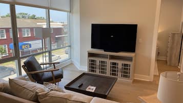 A modern living room with a large window, a flat-screen TV, a sofa, and a coffee table.