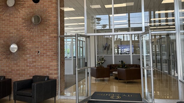Um lobby moderno com entrada de vidro, balcão de recepção e área de estar.