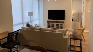 Uma sala de estar moderna com sofá, televisão e luminária no teto.