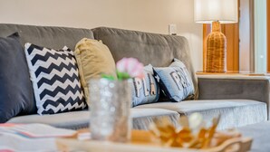 Un canapé gris agrémenté de coussins à motifs, un vase décoratif avec une fleur et une lampe de table.