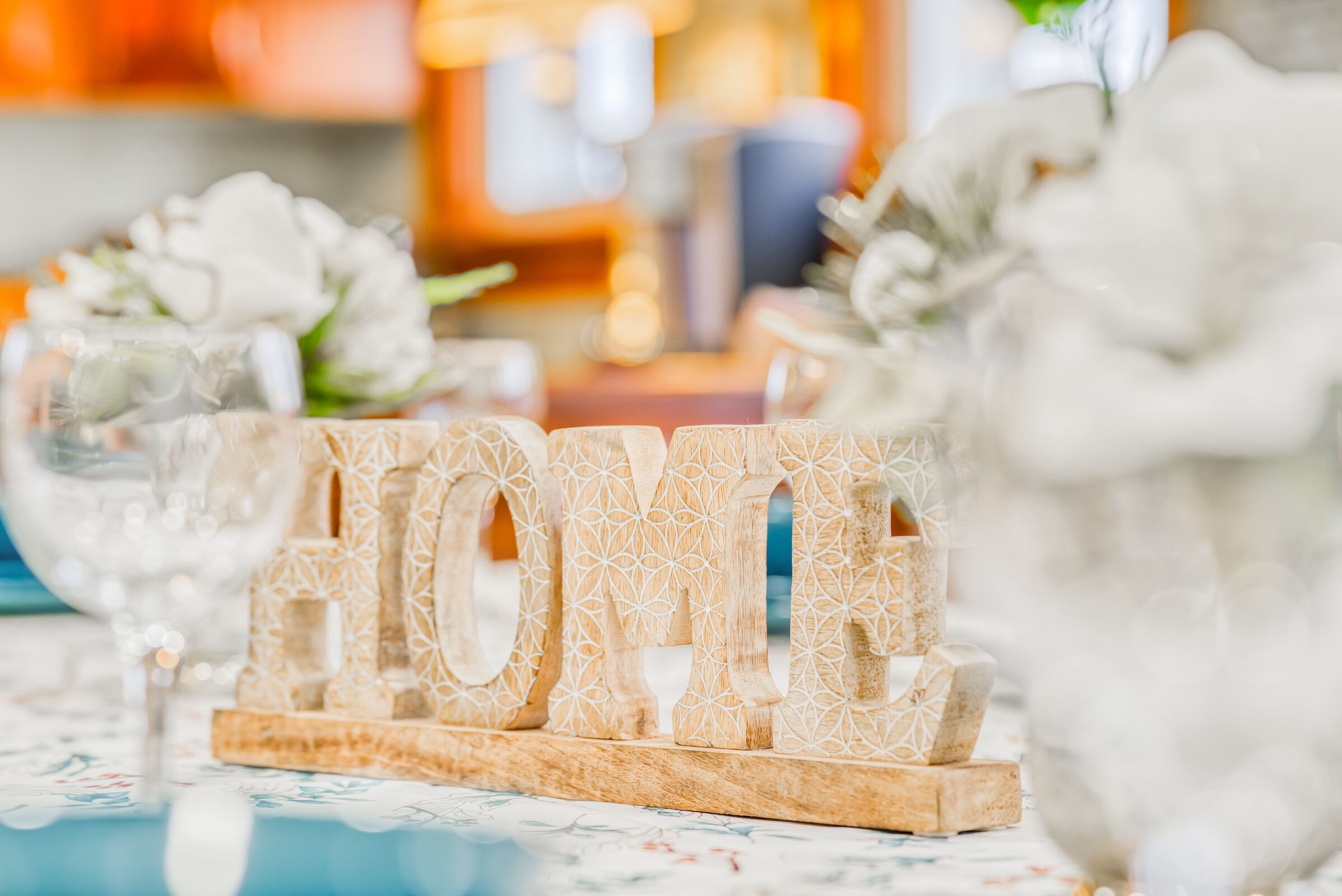 A table with a decorative wooden sign spelling "LOVE" and a glass vase with white flowers.
