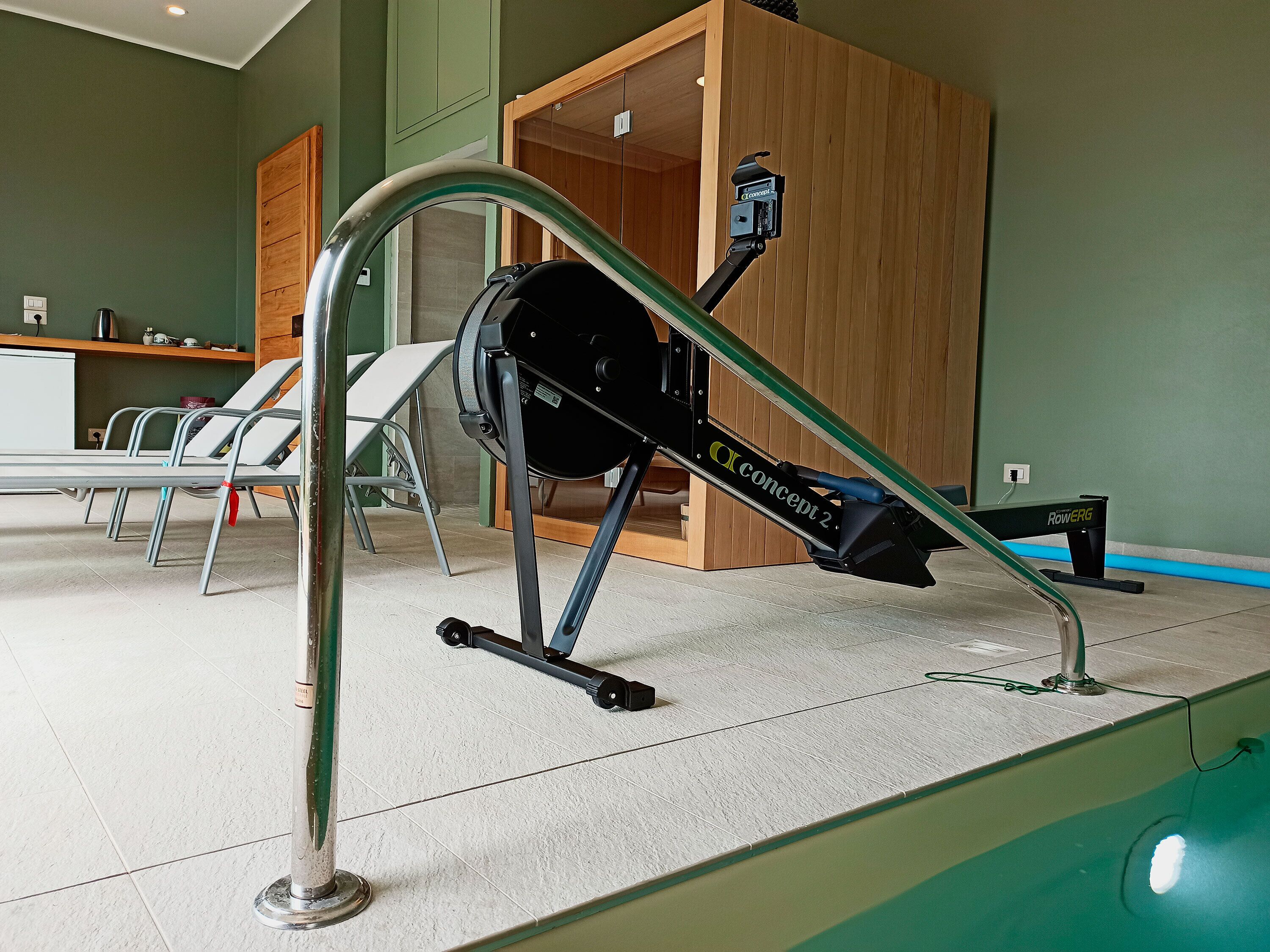 Ein Fitnessraum mit Trainingsgeräten, einer Rezeption und einer Sitzecke mit Stühlen.