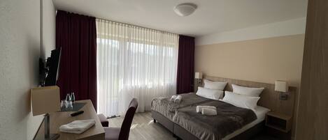 Une chambre d’hôtel avec un lit, un bureau, une chaise et des rideaux.