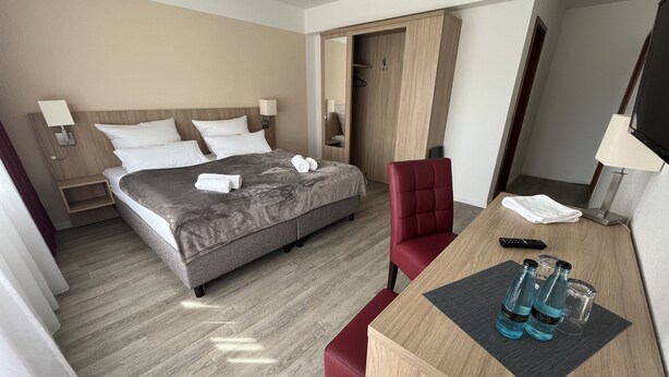 Une chambre d’hôtel comprenant un lit, un bureau avec une chaise, une télévision et une armoire.