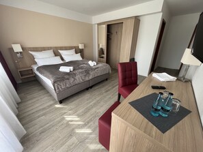 Una habitación de hotel con cama, escritorio, silla, televisión y armario.