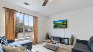 A modern living room with a sofa, a coffee table, and a TV mounted on the wall. - Contemporary and Lux Townhome - 5 mins to FSU (Tallahassee)