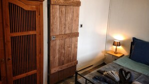 Una habitación con un armario de madera, una cama con almohada azul y una lámpara de noche.