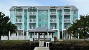 A multi-story building with balconies, a covered area, and a dock extending into a body of water. - Blue Crab Condo at Rivers Edge (Steinhatchee)