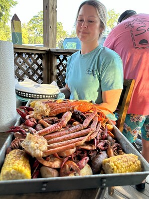 A person seated at a table with a tray of seafood including crabs, shrimp, and corn. - Blue Crab Condo at Rivers Edge (Steinhatchee)