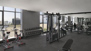 Ein Fitnessraum mit Trainingsgeräten, Kurzhanteln und einer Bank.