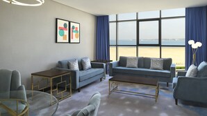 Ein modernes Wohnzimmer mit großem Fenster, einer Couch, einem Couchtisch und einem Glastisch.