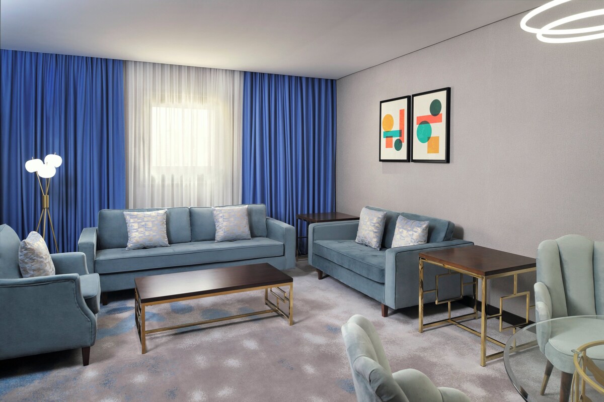 Een moderne woonkamer met een bank, fauteuils, een salontafel en een glazen tafel.