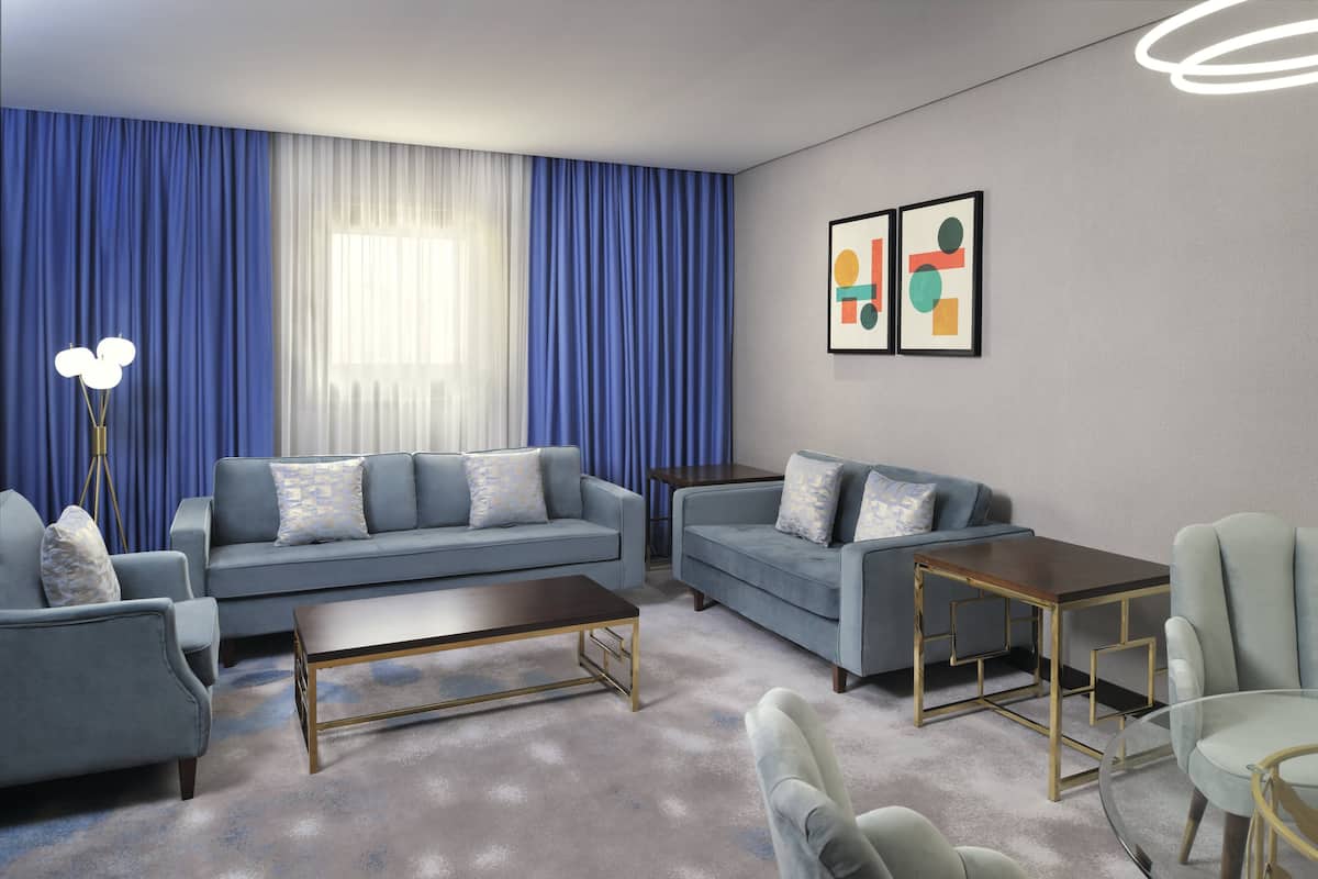 A modern living room with a sofa, armchairs, a coffee table, and a glass table.