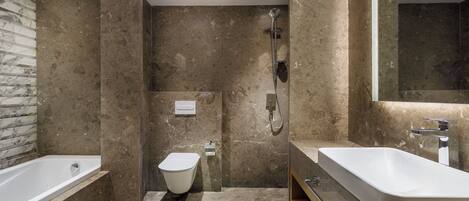A modern bathroom with a bathtub, a toilet, and a large sink.