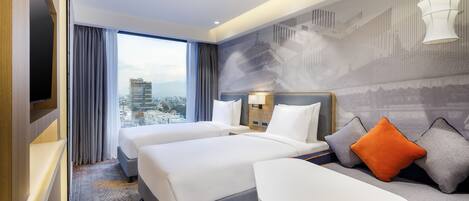 A hotel room with two beds, a sofa, a TV, and a city view.