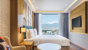 A hotel room with a large bed, a TV, a small table, and a view of a cityscape through a large window. - Holiday Inn Express Kathmandu Naxal by IHG (Kathmandu)