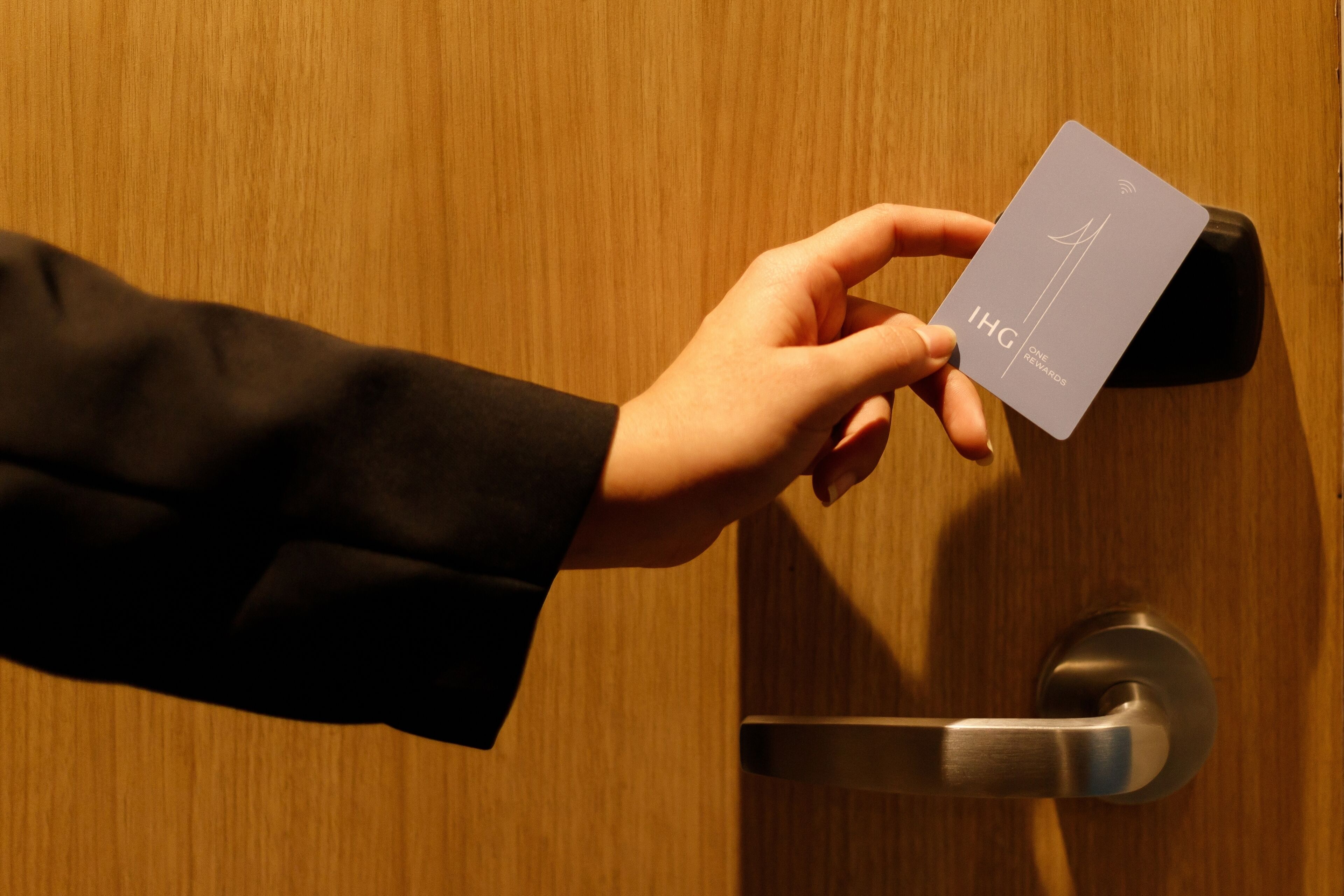 En hånd holder et kort med 'IHG' og 'ONE REWARDS' på.