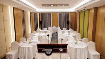 A conference room with multiple round tables, white chairs, and a podium.