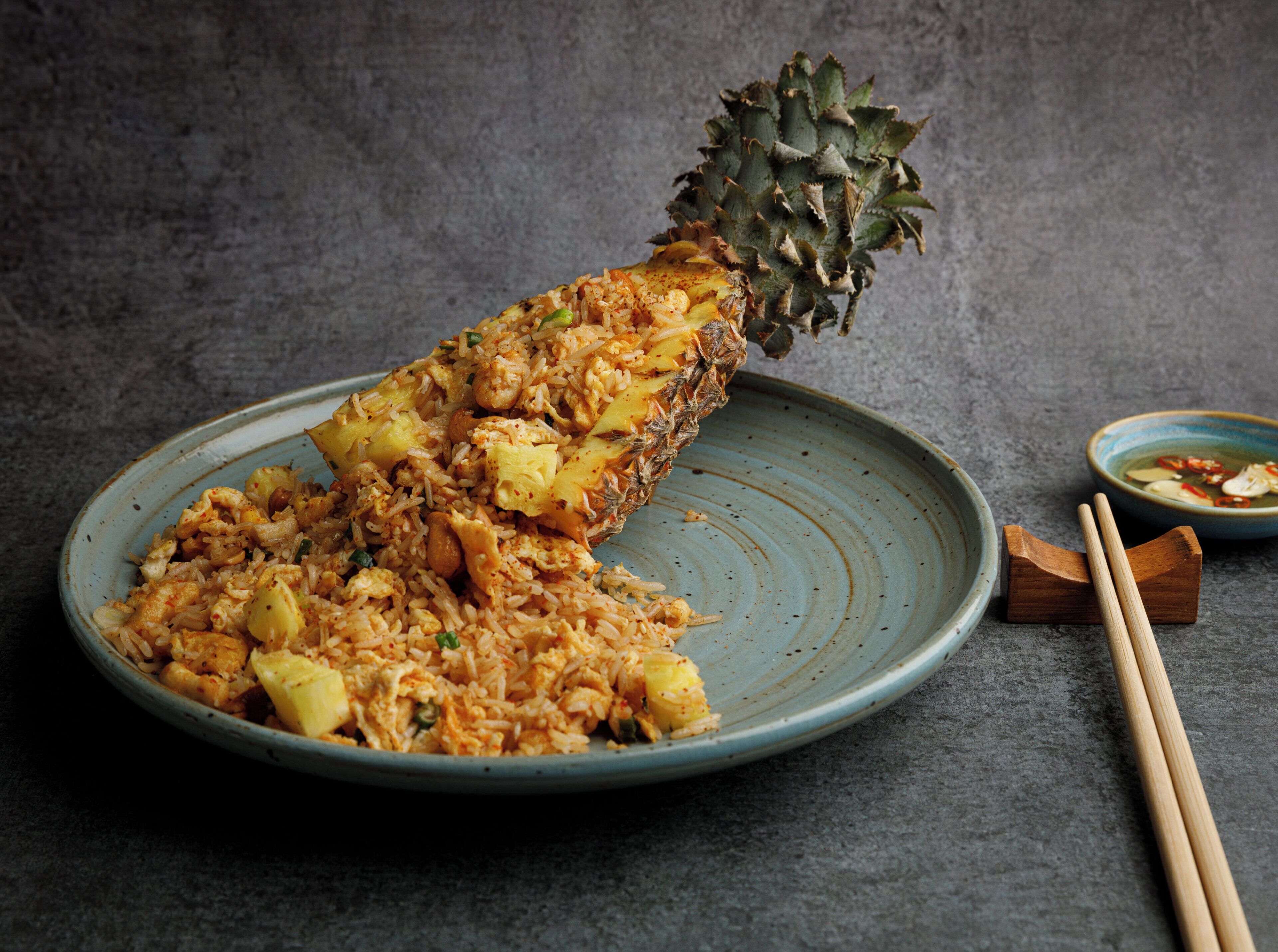 Une assiette de riz frit aux ananas, servie dans une assiette en céramique bleue.