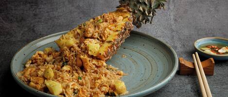 Um prato de arroz frito com abacaxi sobre um prato cerâmico azul.