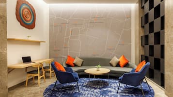 Un salón moderno con un mural de mapa, una mesa de centro redonda y dos sillones azules.