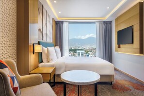 A hotel room with a bed, a desk, a chair, a TV, and a view of a cityscape. - Holiday Inn Express Kathmandu Naxal by IHG (Kathmandu)
