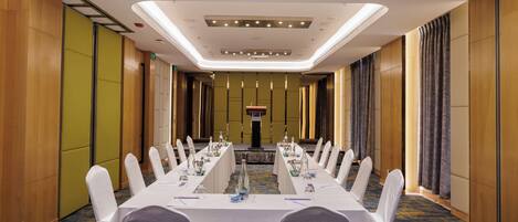 A conference room with a long table, chairs, and a podium.