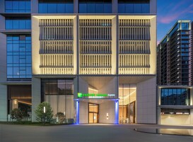 A modern hotel building with a prominent entrance, large windows, and a well-lit facade.