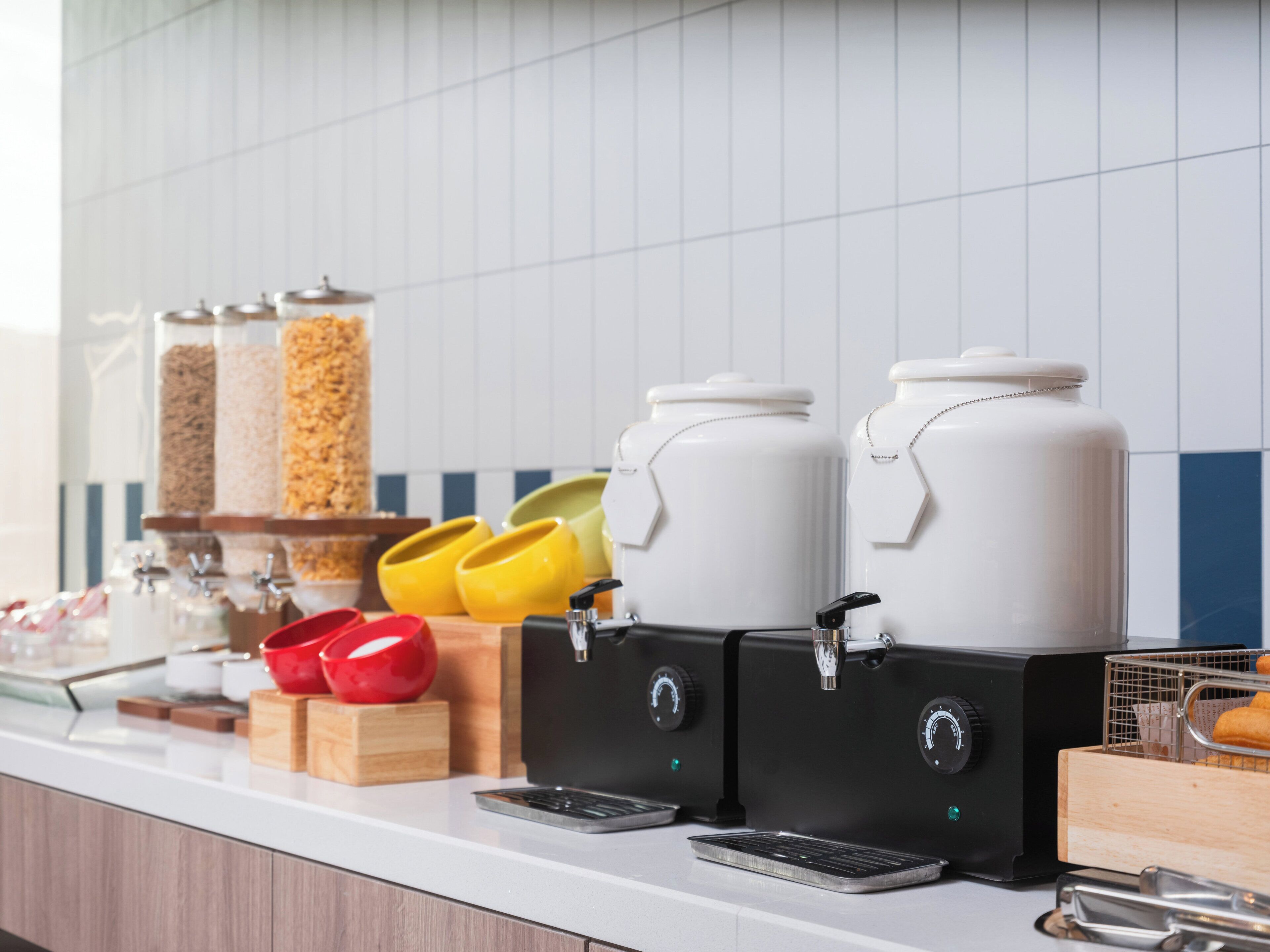 A kitchen counter with coffee makers, condiment dispensers, and a food warmer.