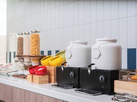 A kitchen counter with coffee makers, condiment dispensers, and a food warmer.