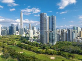 A high-rise building with a modern glass facade, surrounded by a well-maintained park with green lawns and trees.