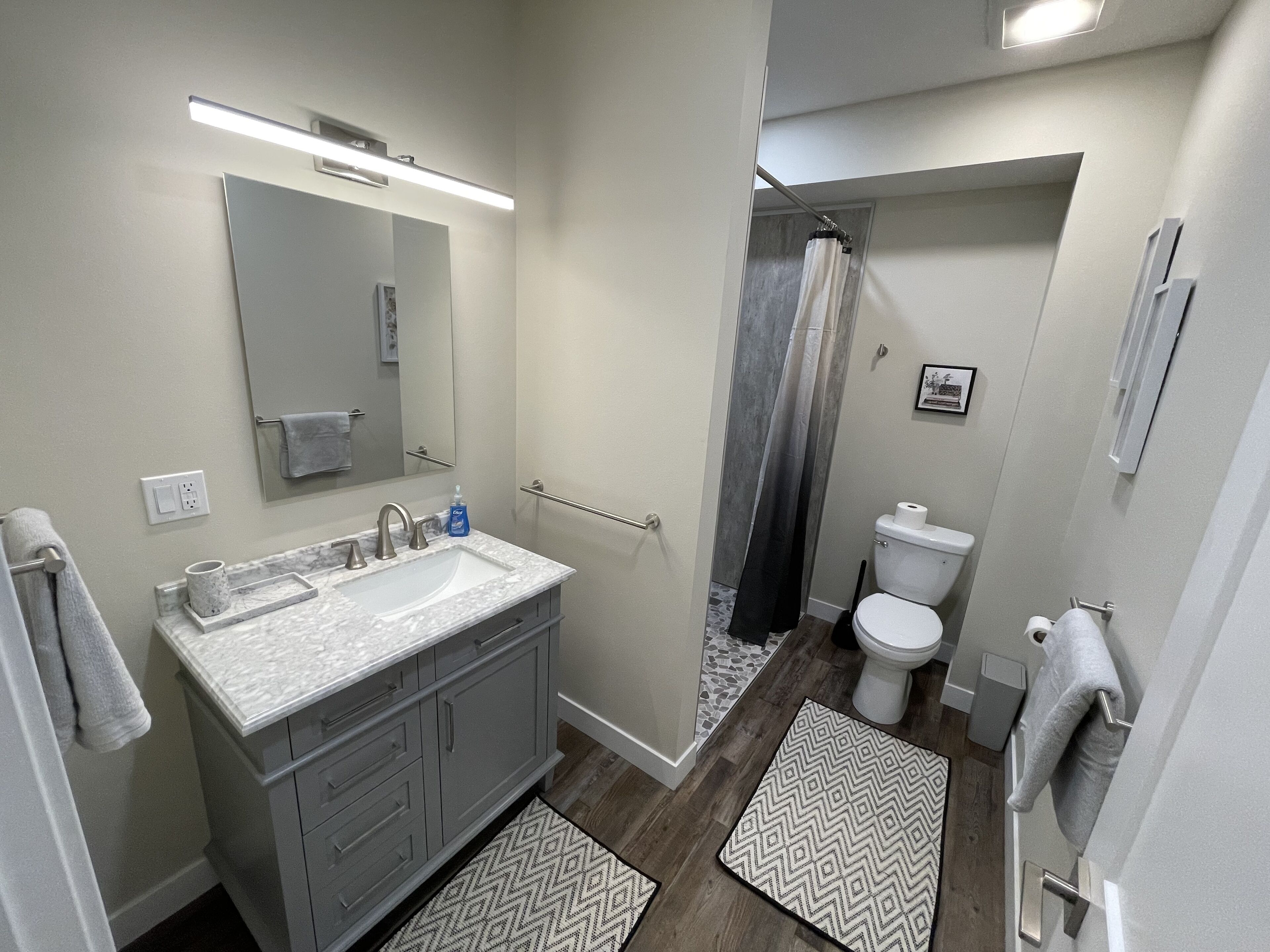 A modern bathroom with a marble sink, a toilet, and a shower area.