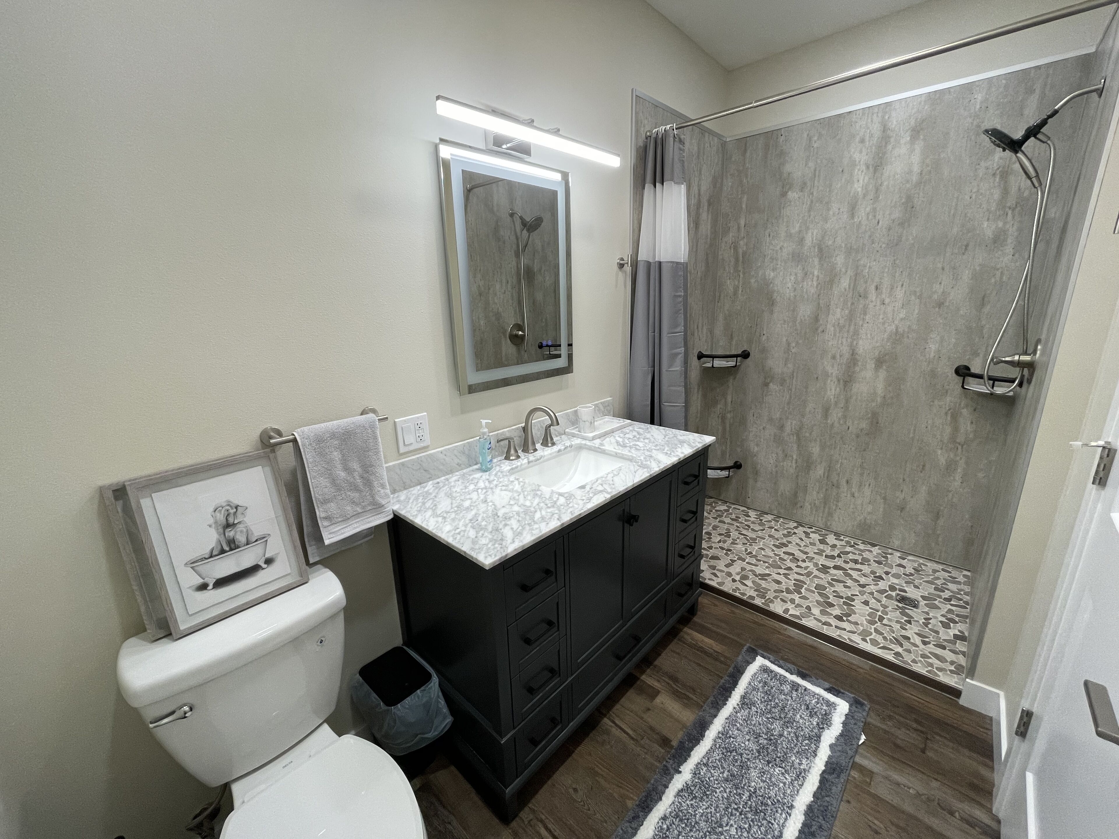 A modern bathroom with a toilet, sink, vanity, and shower.