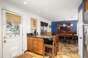 A kitchen with a wooden island, a dining table with chairs, and a built-in wine rack. - Home on the Range Near Glacier Park (Columbia Falls)