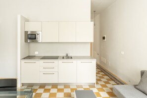 Uma cozinha moderna com armários brancos, micro-ondas e pia.