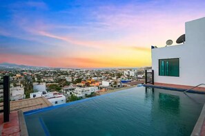 A rooftop infinity pool with a cityscape view at sunset. - Enjoy a fully equipped private and elegant condo in a luxury building.  (Cabo San Lucas)